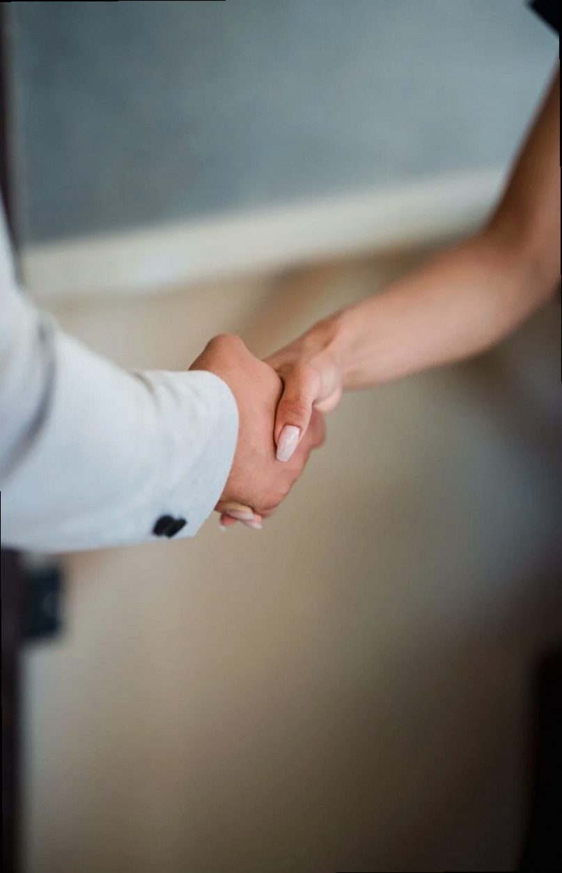 A close-up view of a handshake between two professionals, symbolizing agreement and partnership.